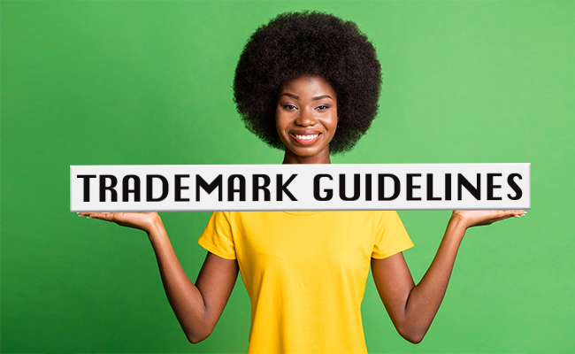 Woman on green background holding sign that reads, "Trademark Guidelines"
